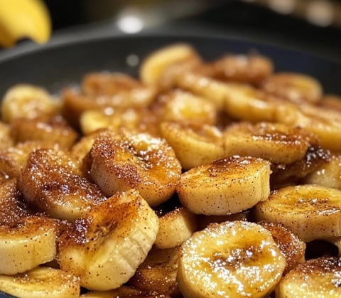 A bowl of sweet bananas with sugar sprinkled on top.