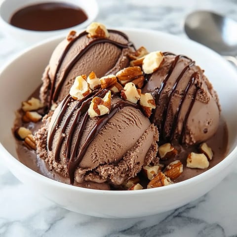 Ice cream in a bowl with nuts and fudge sauce.